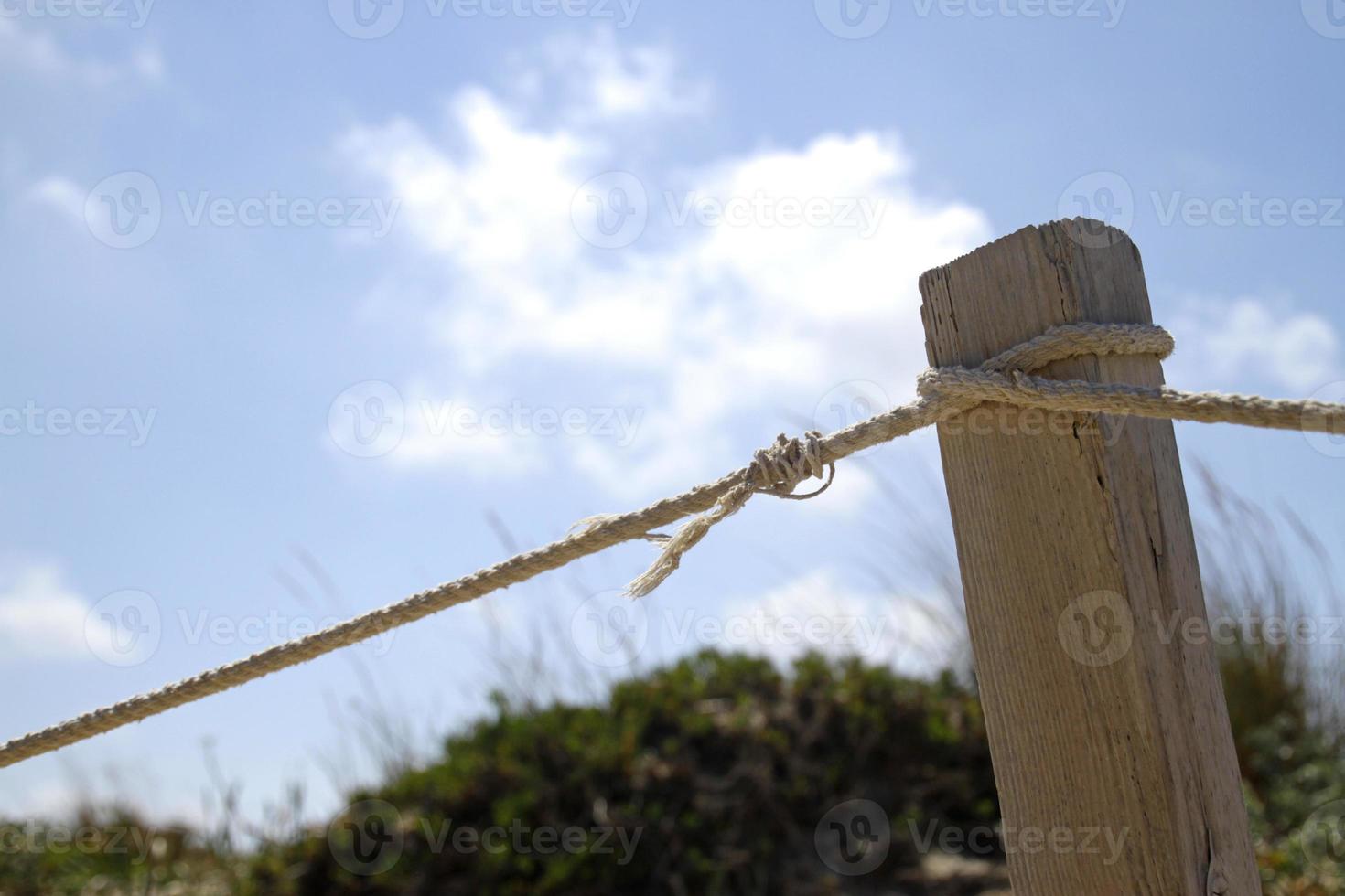 Wooden post with rope at the beach on a sunny day photo