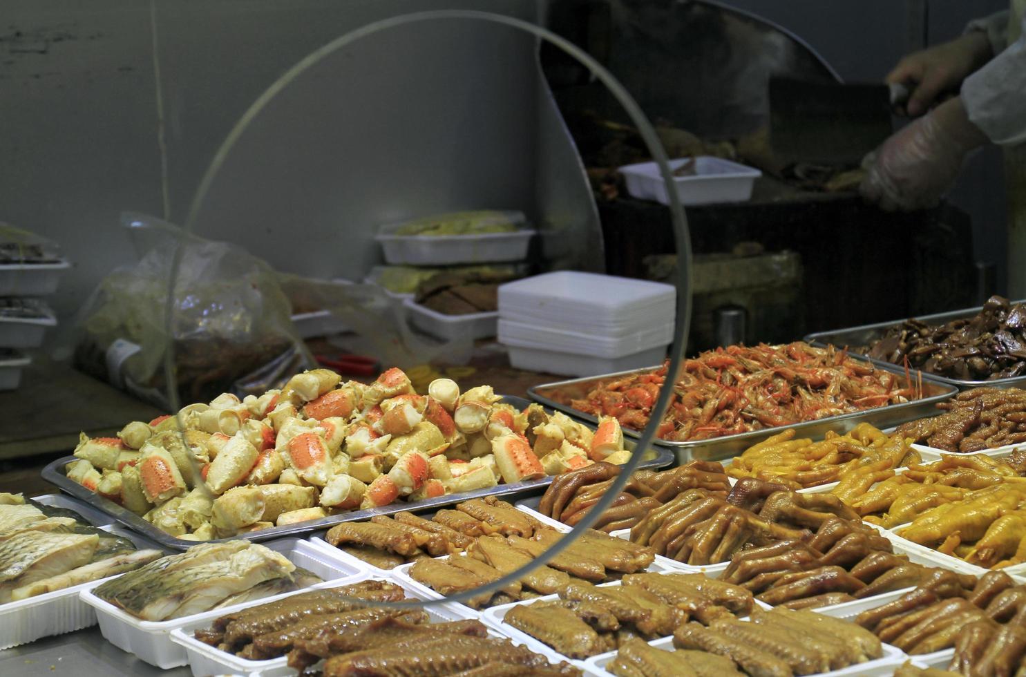 shanghai, china - 15 de abril de 2018 - un vendedor ambulante en shanghai ofrece una variedad de carnes y mariscos en la exhibición de su tienda. foto