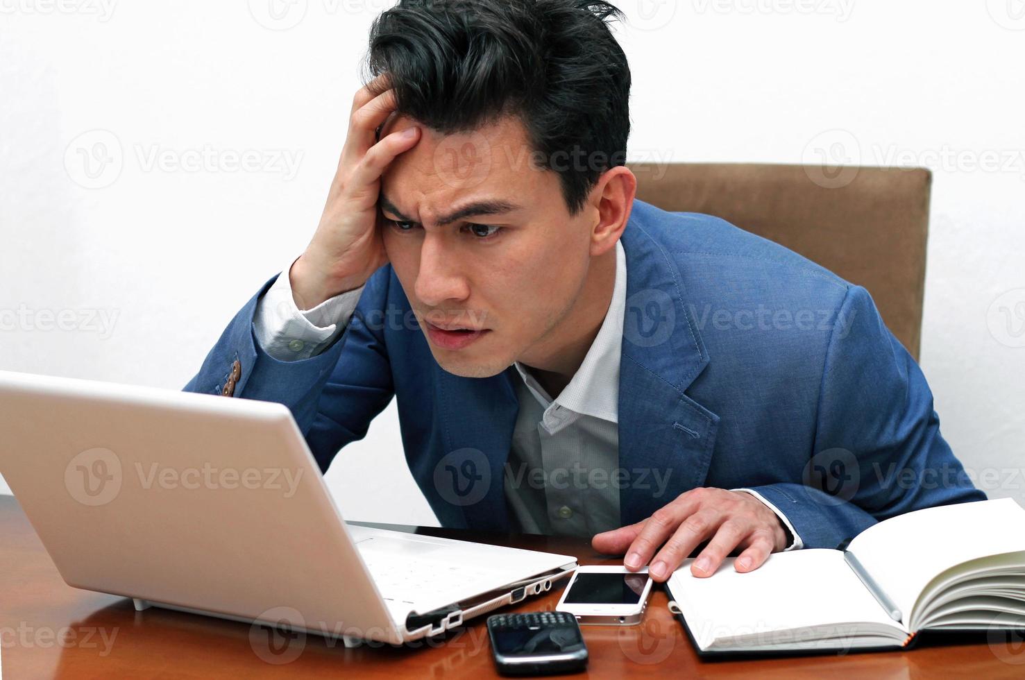 hombre con mirada preocupada y confundida sosteniendo escuchar mientras mira la computadora portátil foto