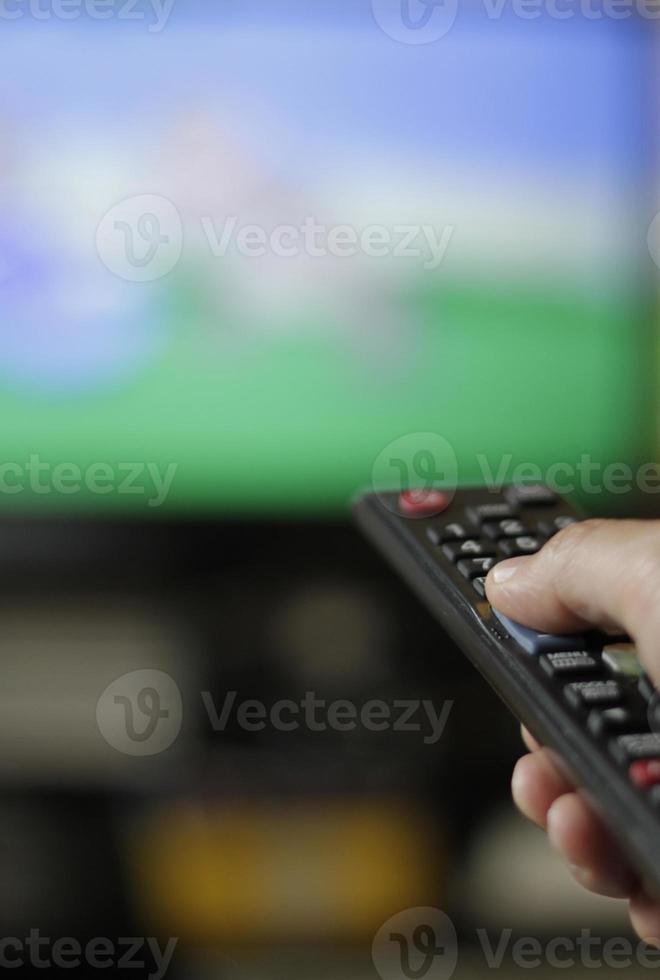 Holding a TV remote control and switching channels photo