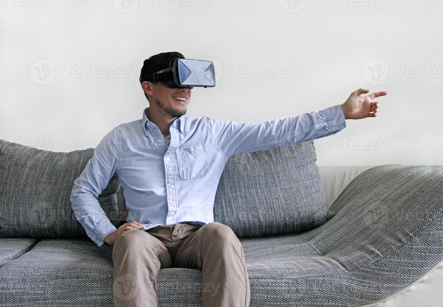 Man wearing virtual reality goggles points to the right with his arm photo