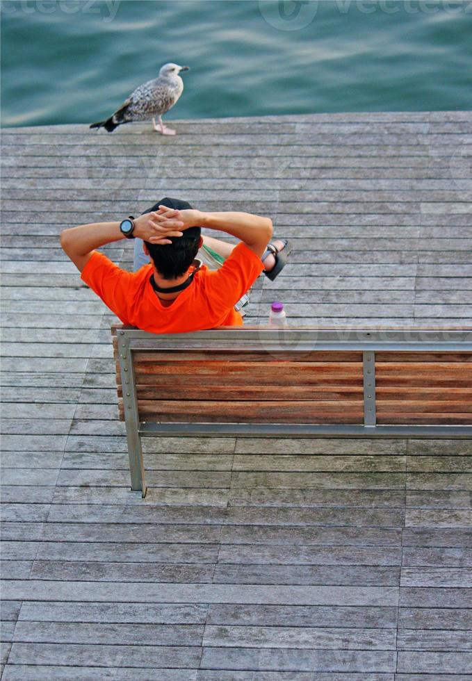 Man with orange t-shirt relaxing at Barcelona Bay photo