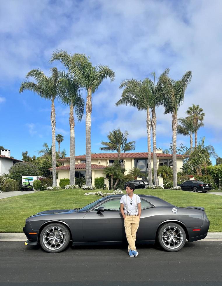 los angeles, usa - 12 de julio de 2022 - hombre apoyado contra un dodge challenger en california foto