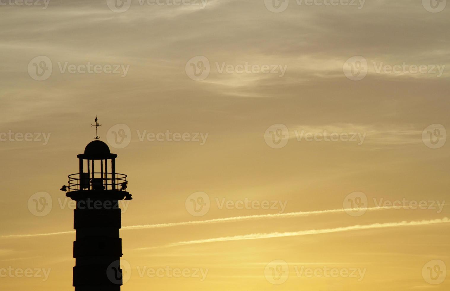 A lighthouse stands out against the golden sky during a sunset in Lisbon, Portugal photo