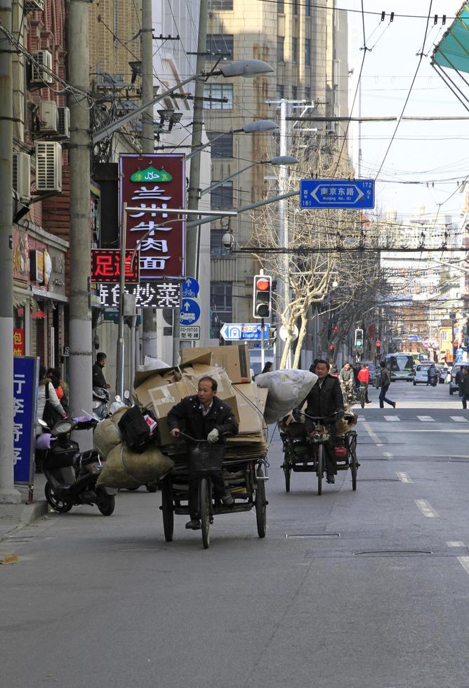 Shanghai, China - April 15, 2018 - Men on bicycles stacked with cardboard cycling through the streets of Shanghai. photo