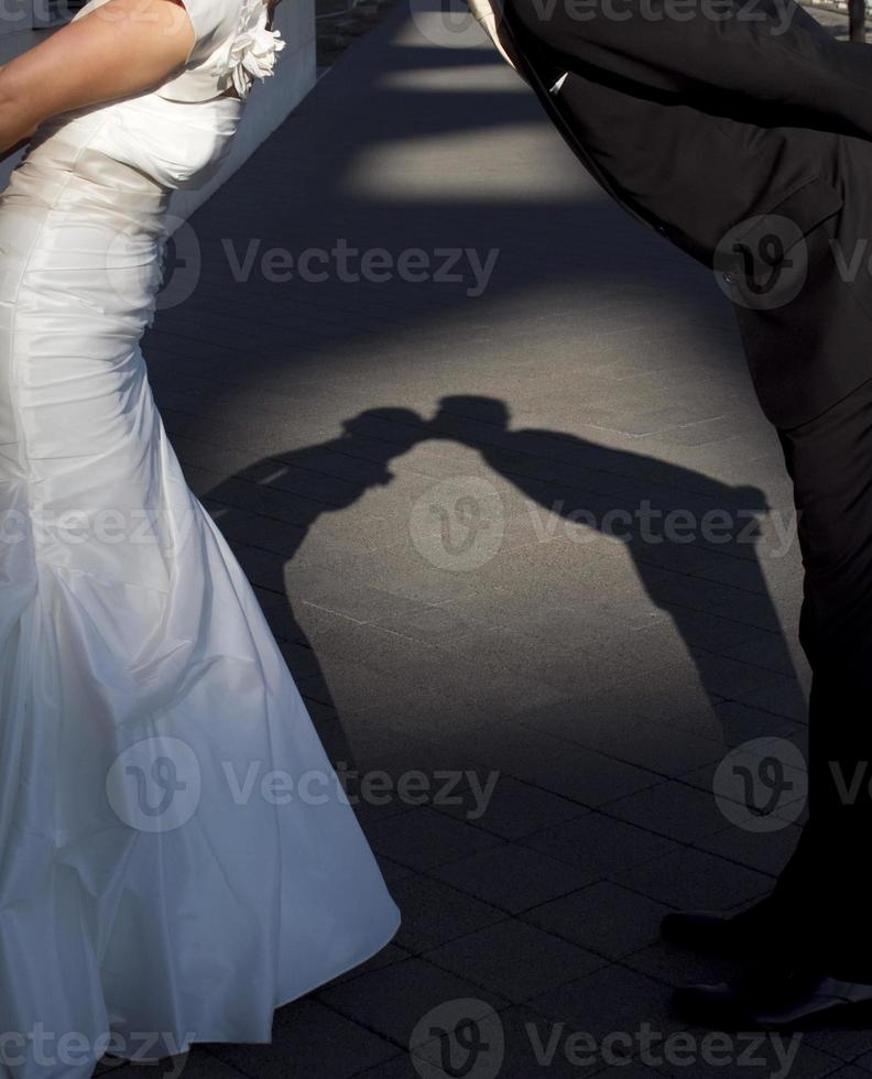 Shadow of newlywed couple leaning forward and kissing photo