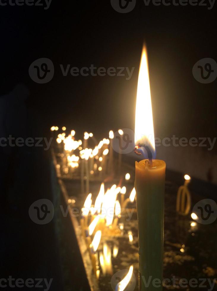 Many candles burning in a dark room photo