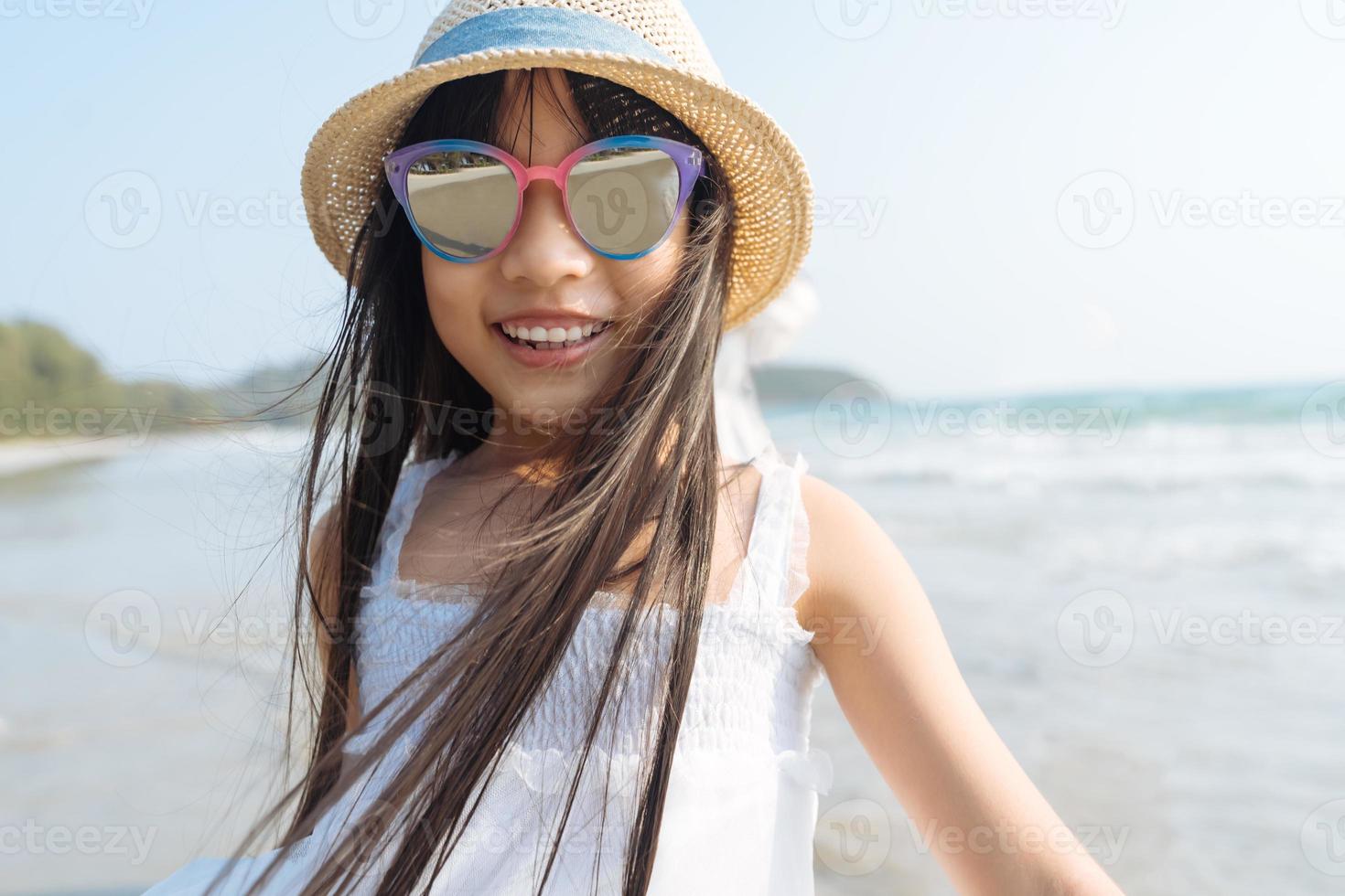 Portrait little Asian girl at sea beach looking at camera happy vacation concept photo