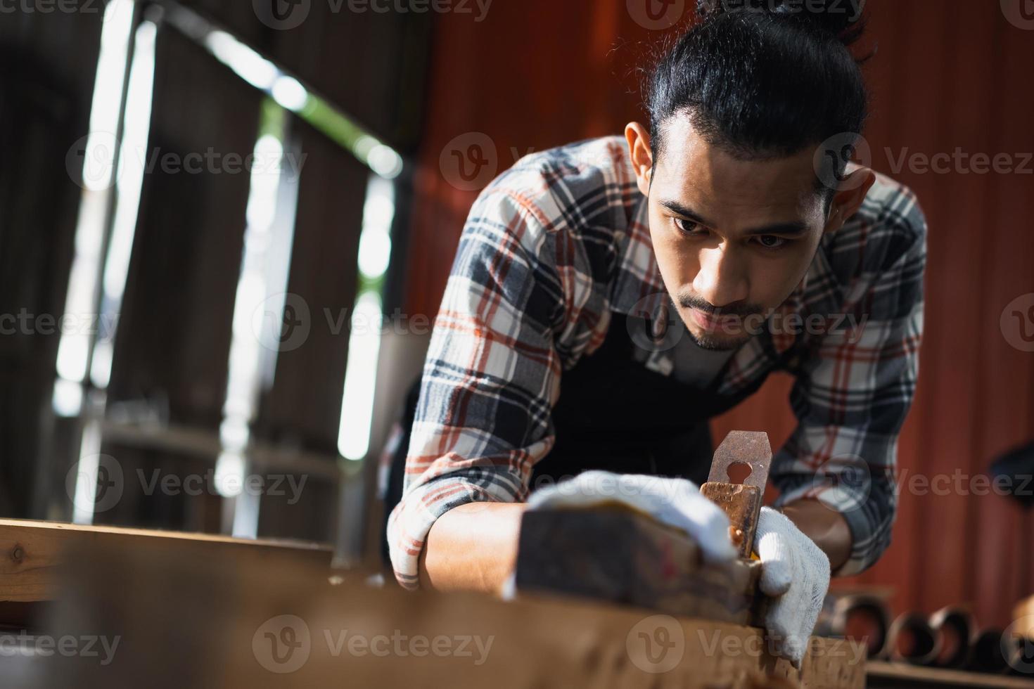 Young Asian man Carpenter working in woodcraft carpentry workshop. photo