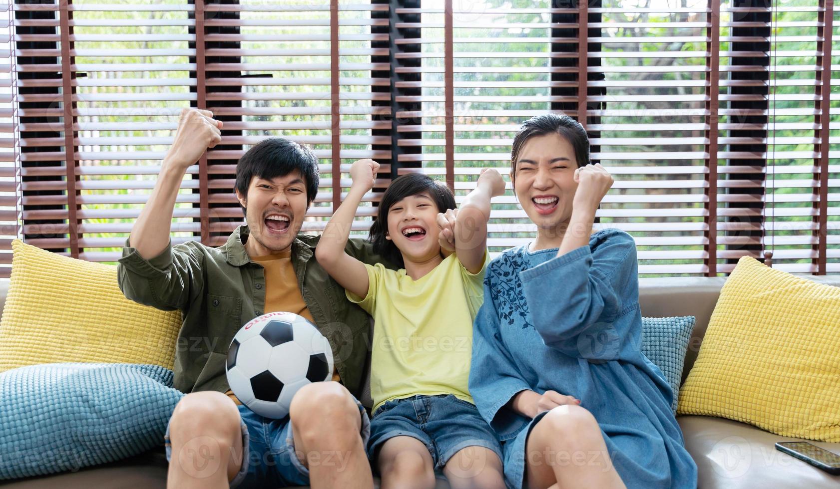 familia asiática viendo partidos de fútbol en la televisión y reaccionando feliz saliendo cuando el equipo dispara la pelota al gol. foto