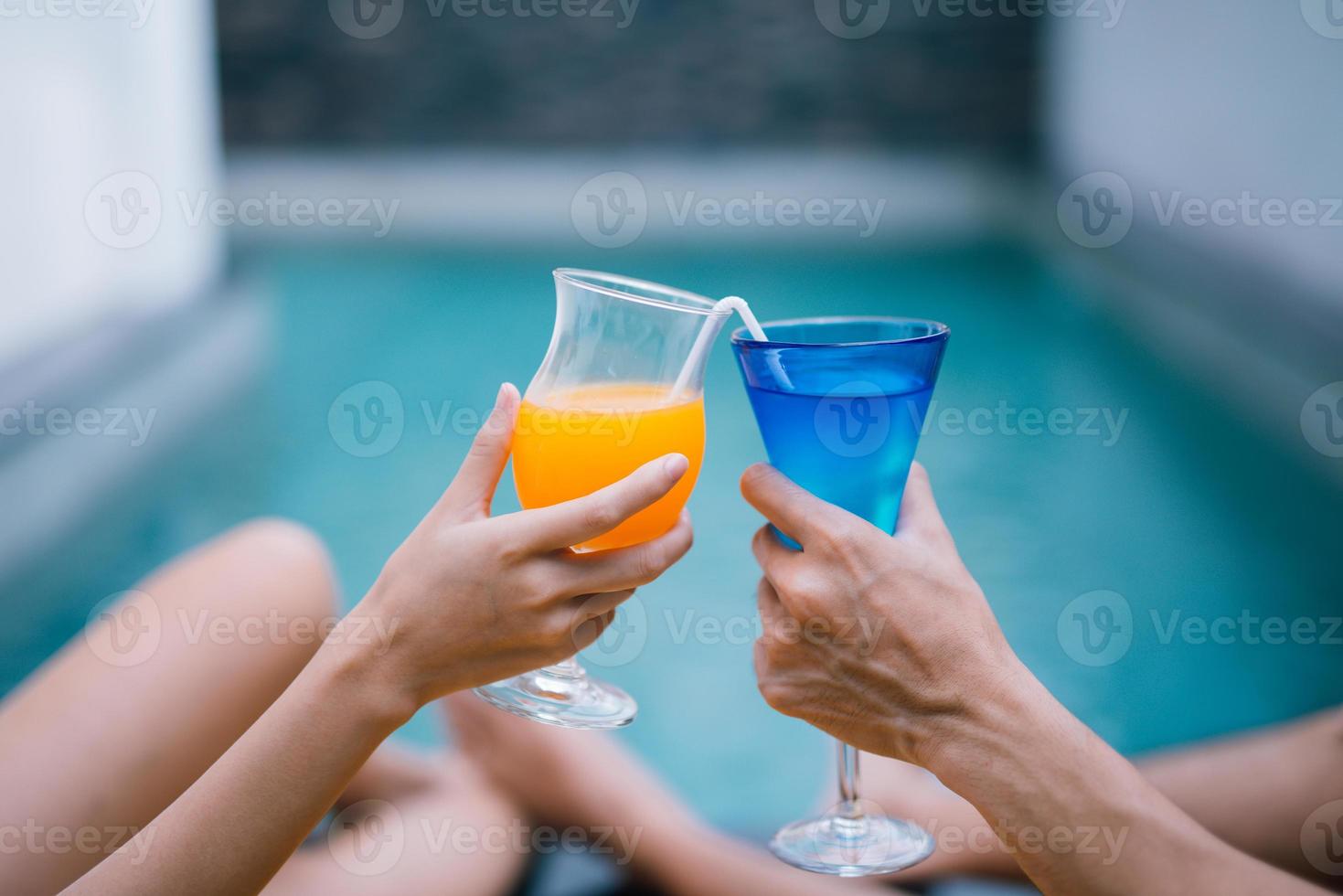 Hands holding juice glasses by the pool summer time. 10320337 Stock