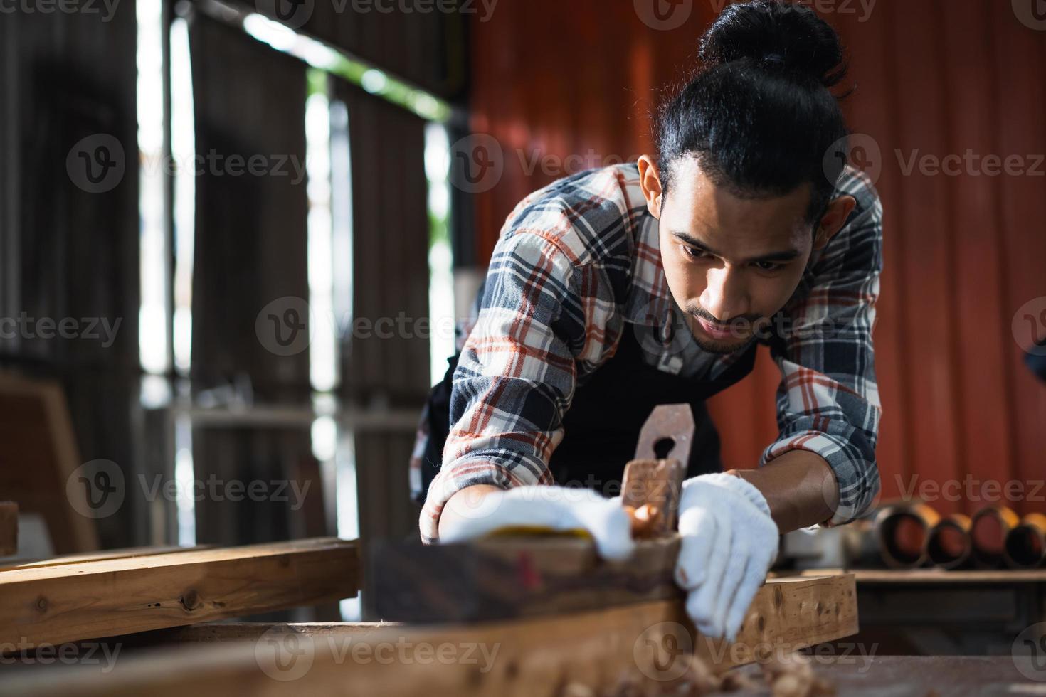 joven carpintero asiático que trabaja en un taller de carpintería de madera. foto