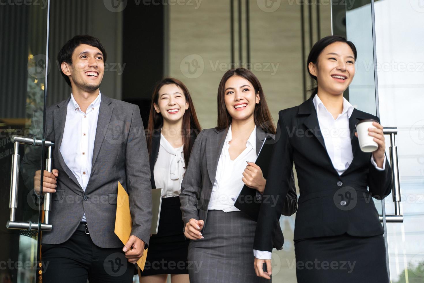 Asian business people walking to go out office building photo