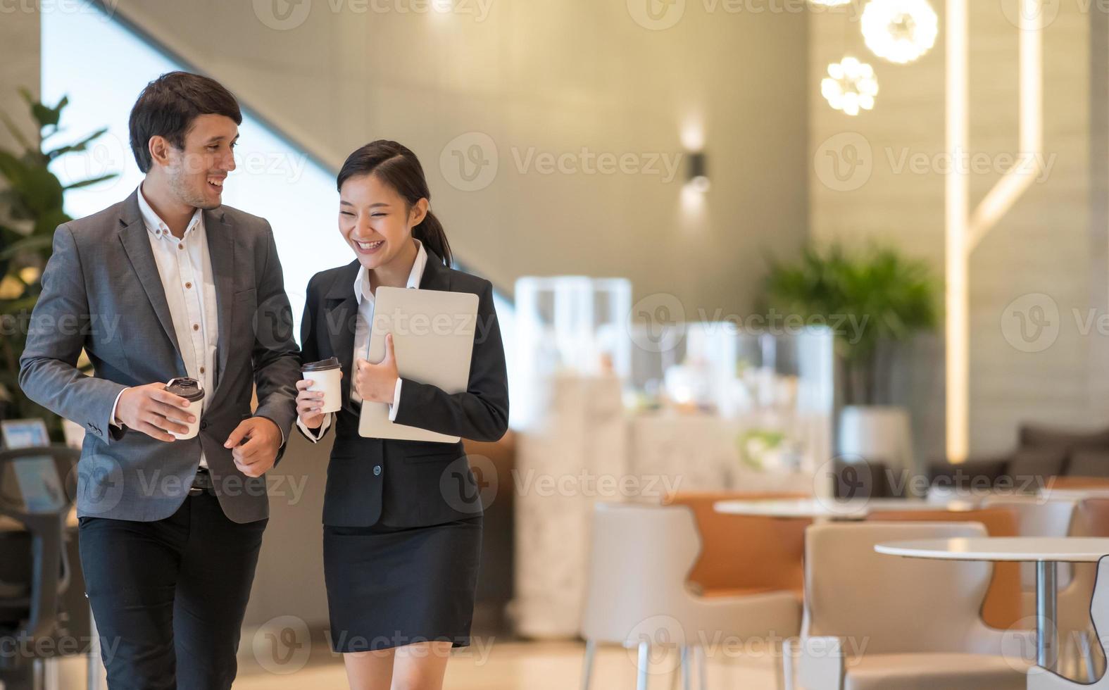 empresarios asiáticos caminando en el edificio de oficinas. joven empresario y empresaria hablando al caminar. foto