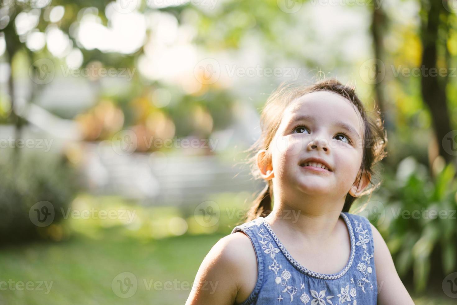 portrait little girl in nature park . cute kids looking up photo