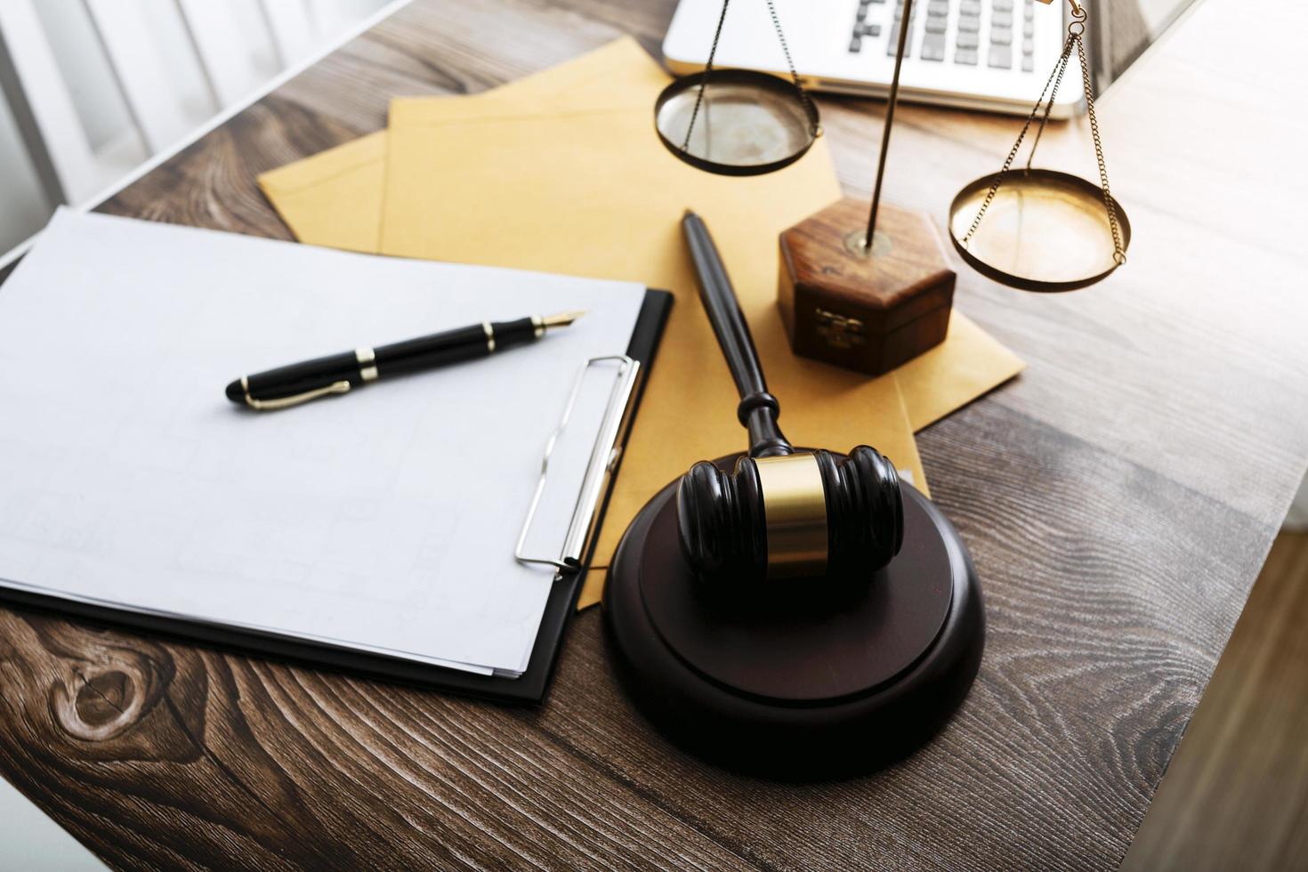 Justice and law concept.Male judge in a courtroom with the gavel, working with, computer and docking keyboard, eyeglasses, on table in morning light photo