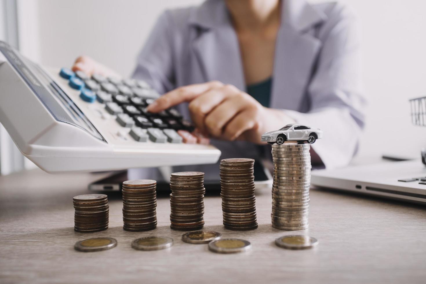 Close up of hand putting coin on pile coins for saving money. Collect money to buy a new car, saving and car loan concept. Flat lay photo