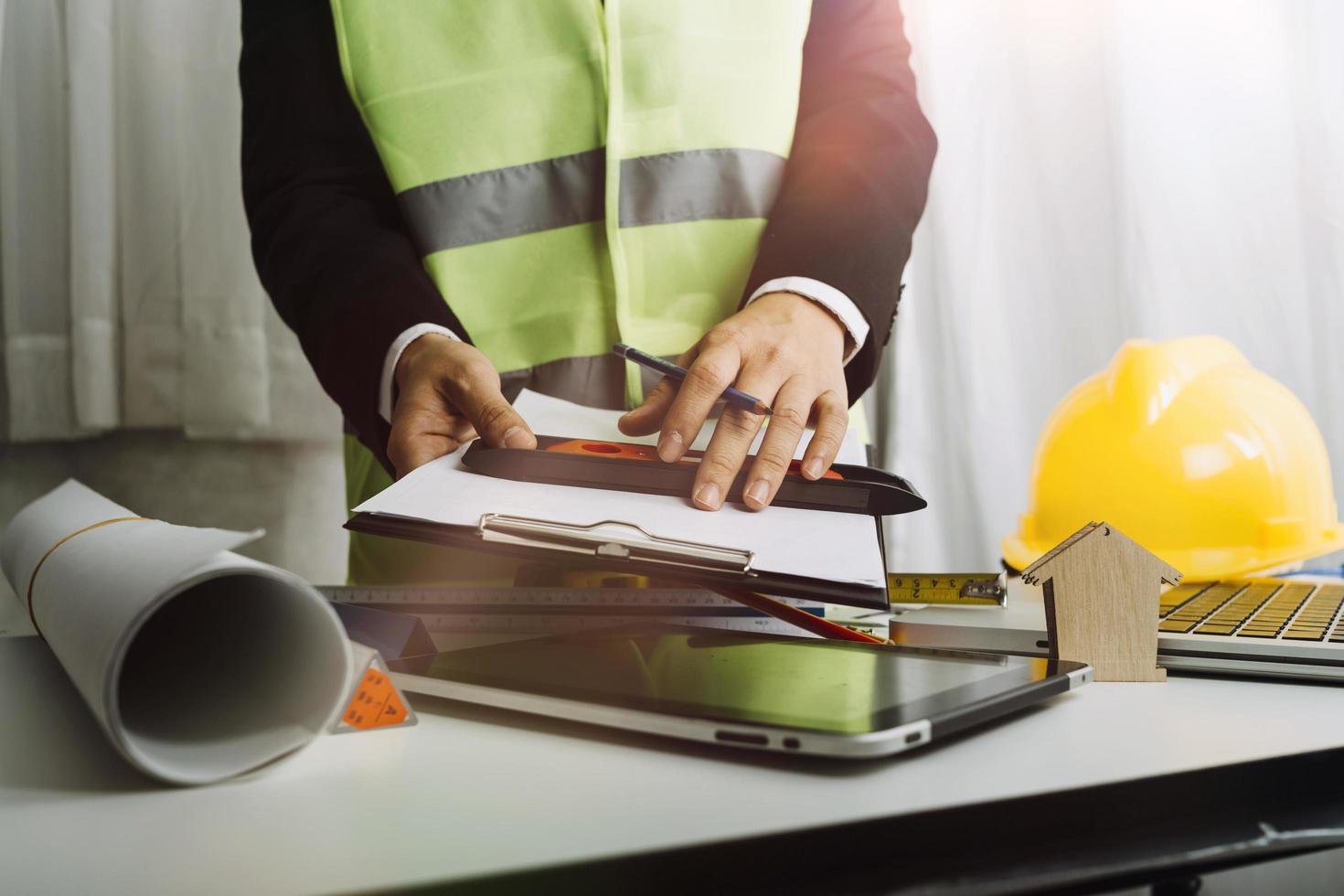 Dos colegas discutiendo el trabajo de datos y una tableta, un portátil con un proyecto arquitectónico en el sitio de construcción en un escritorio en la oficina foto