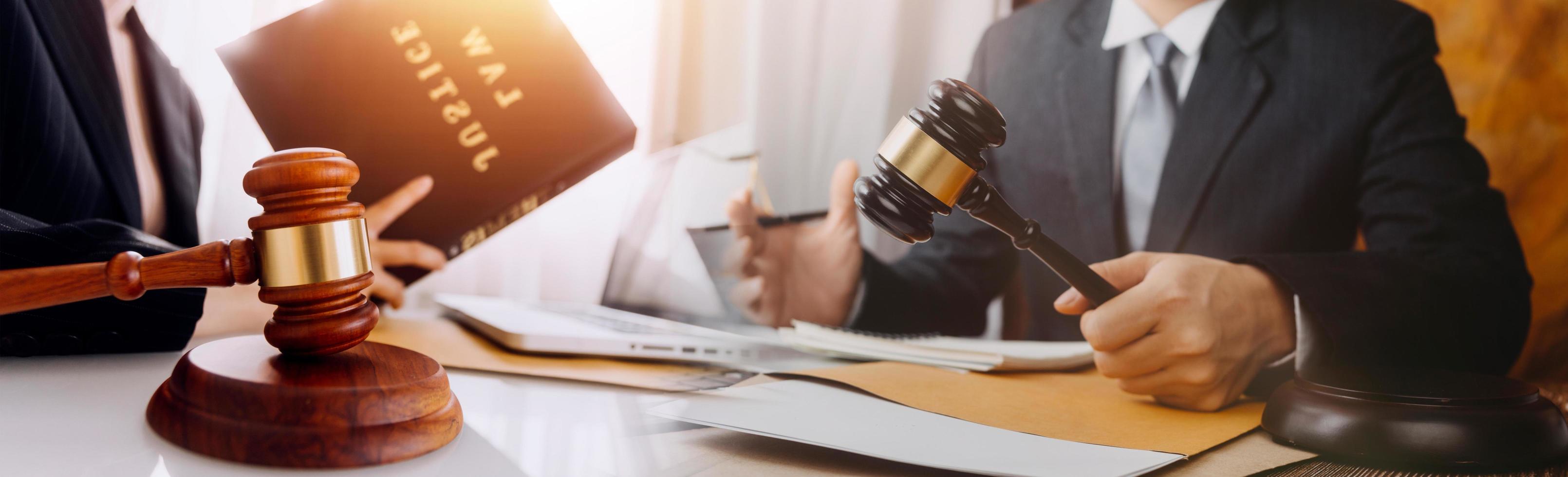 Justice and law concept.Male judge in a courtroom with the gavel, working with, computer and docking keyboard, eyeglasses, on table in morning light photo