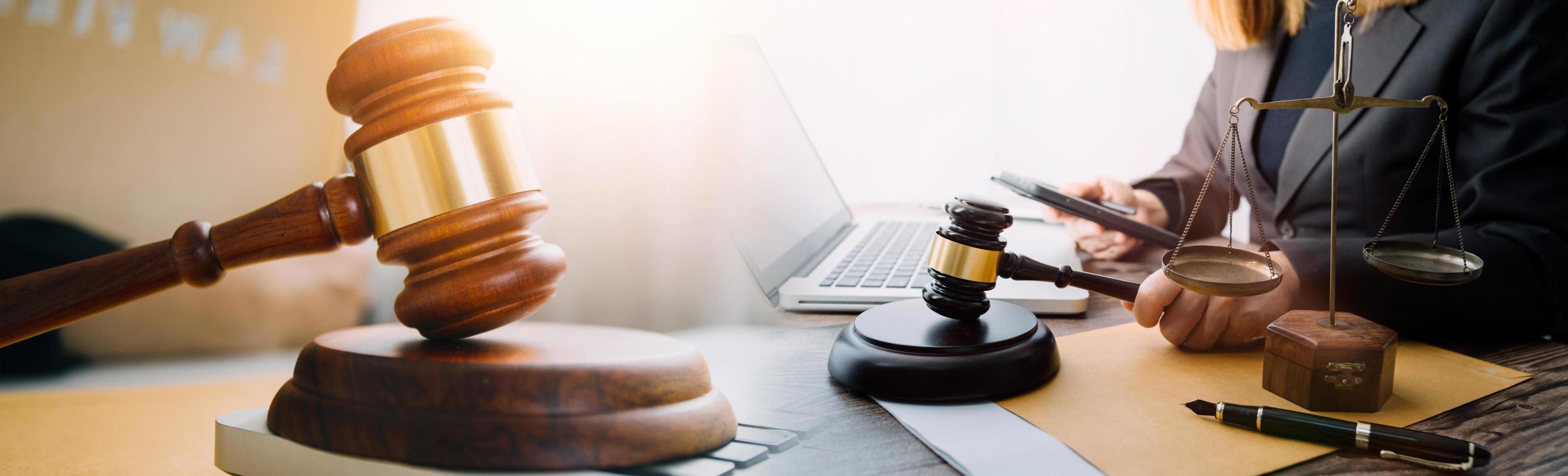 Justice and law concept.Male judge in a courtroom with the gavel, working with, computer and docking keyboard, eyeglasses, on table in morning light photo