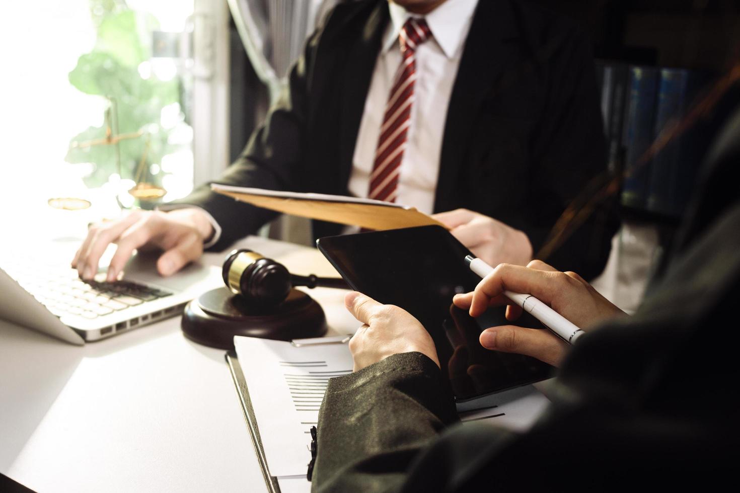 Business and lawyers discussing contract papers with brass scale on desk in office. Law, legal services, advice, justice and law concept picture with film grain effect photo