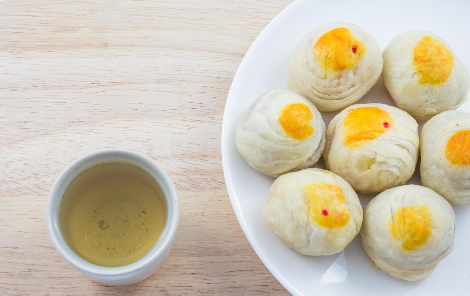 Chinese Pastry Mung Bean or Mooncake with Egg Yolk on dish wooden table and green tea cup photo