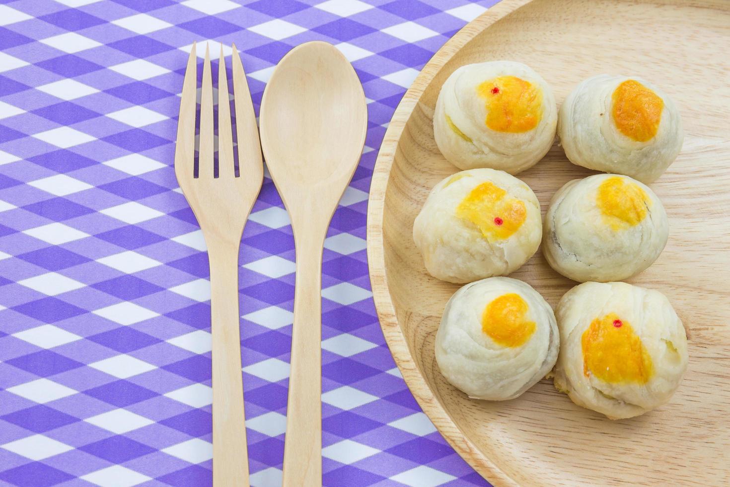 Chinese Pastry Mung Bean or Mooncake with Egg Yolk on wooden dish and spoon fork striped cloth photo