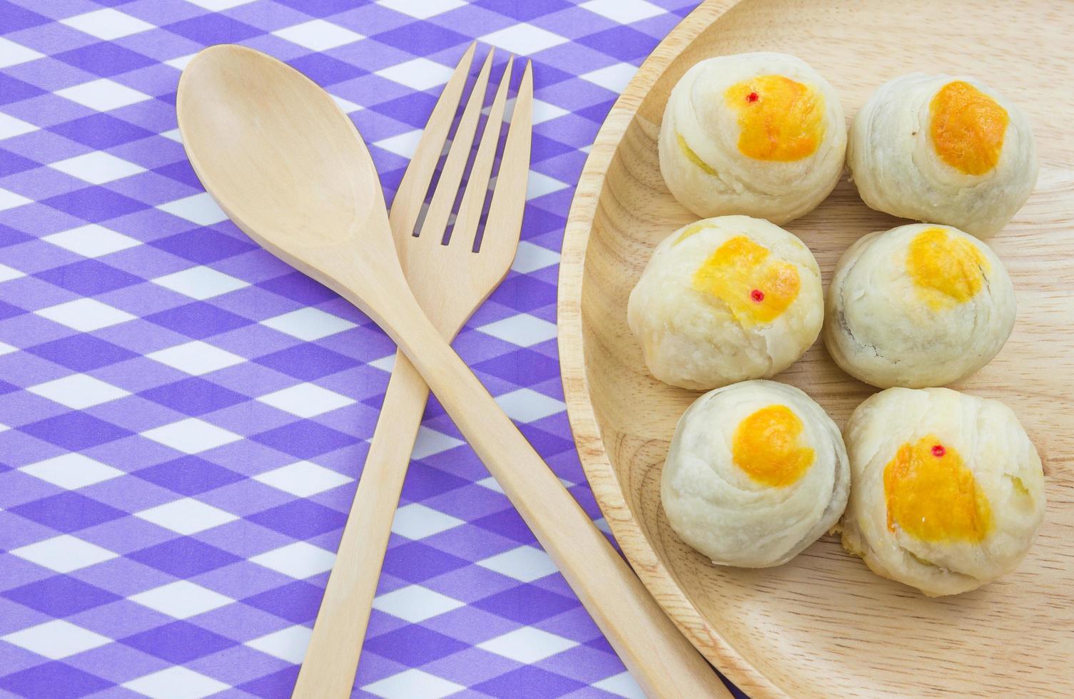 Chinese Pastry Mung Bean or Mooncake with Egg Yolk on wooden dish and spoon fork striped cloth photo