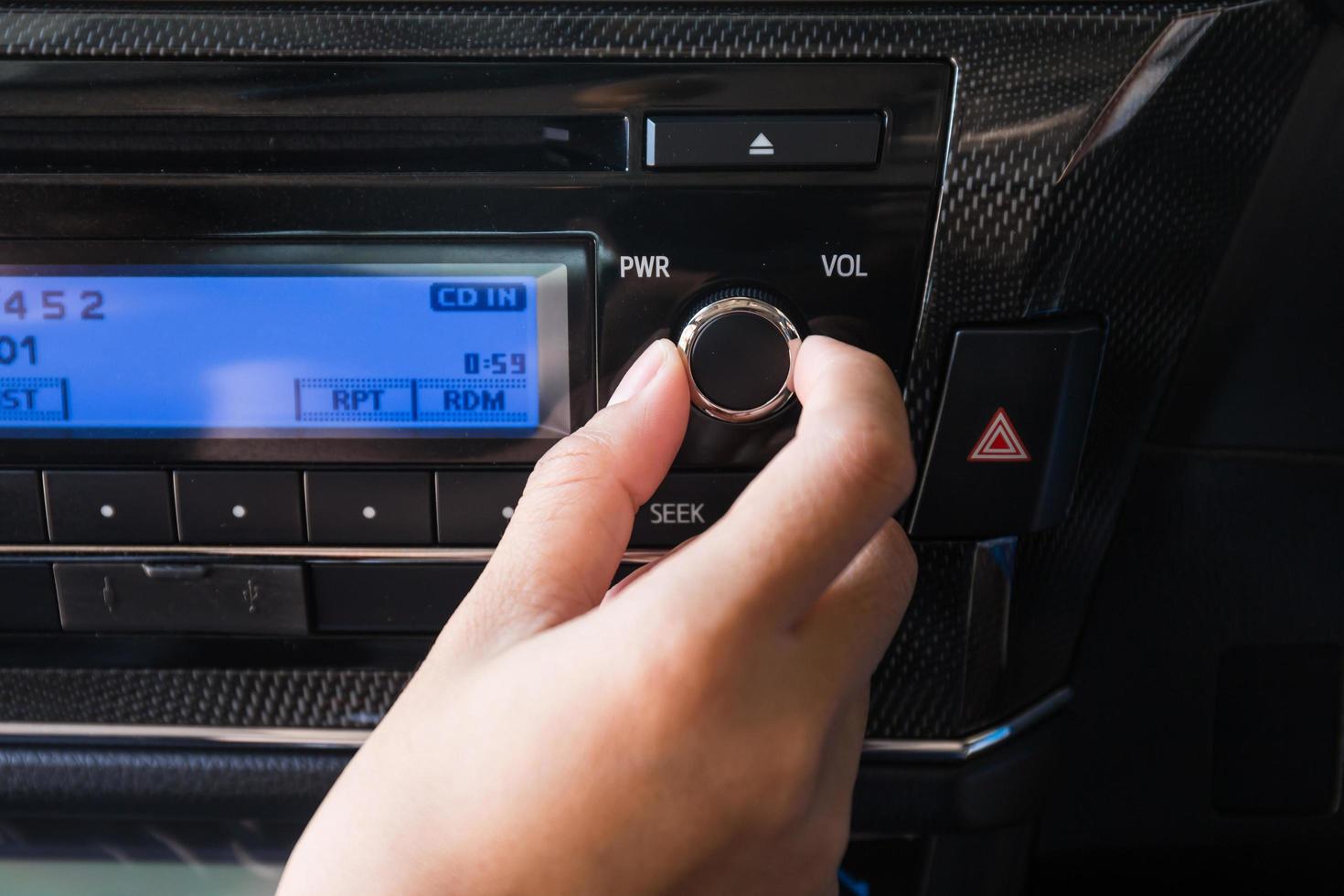 mujer que usa el control de audio del volumen del automóvil. foto