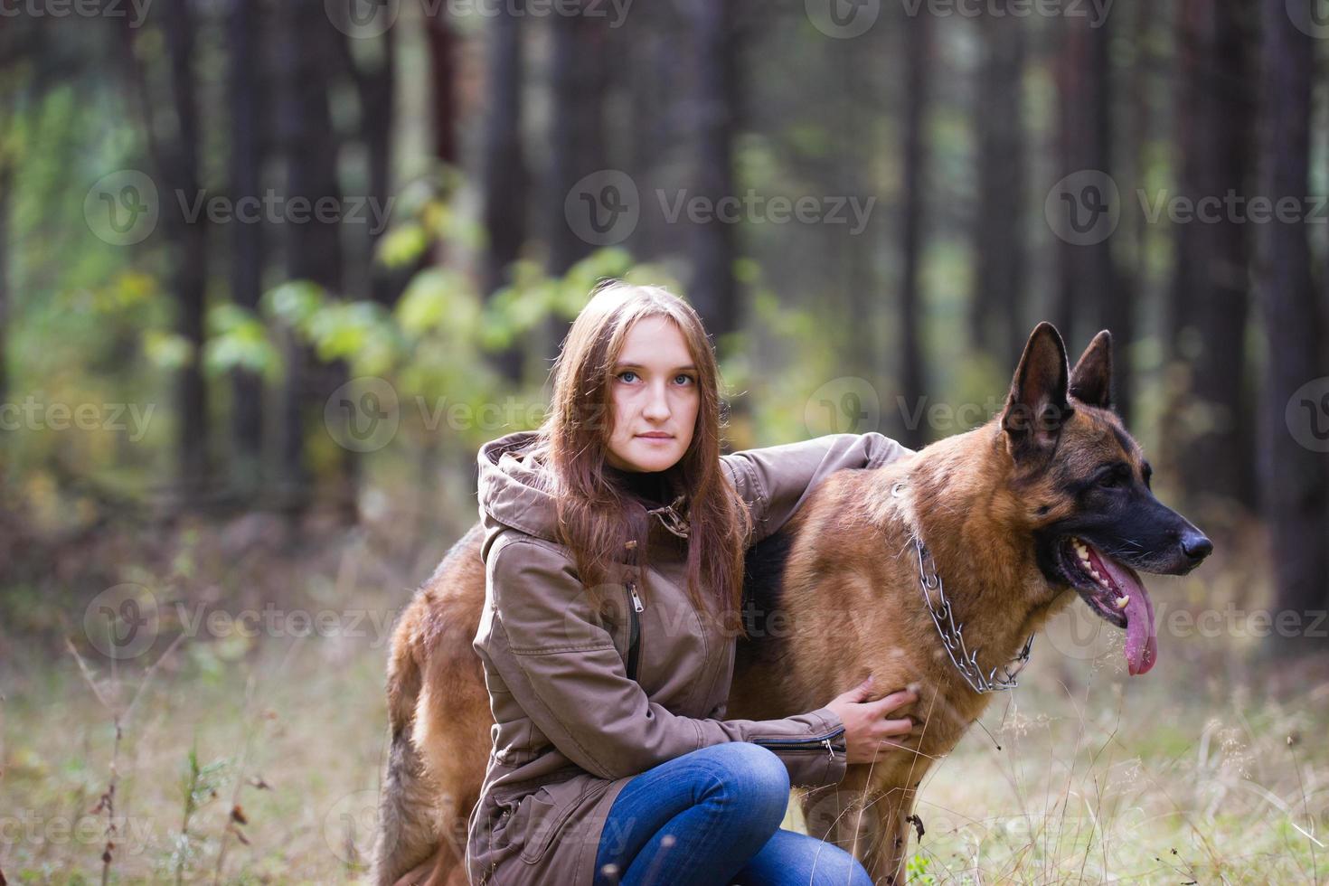 Young attractive woman posing with German Shepherd dog outdoors in the autumn park, close up photo