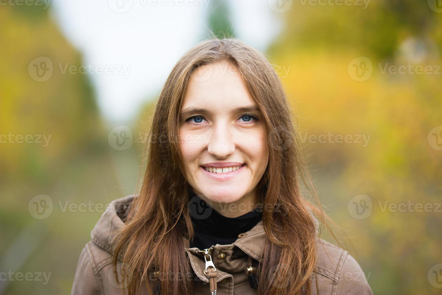 Portrait of young cute woman in fall autumn park. Beautiful caucasian girl walking in forest, close up photo