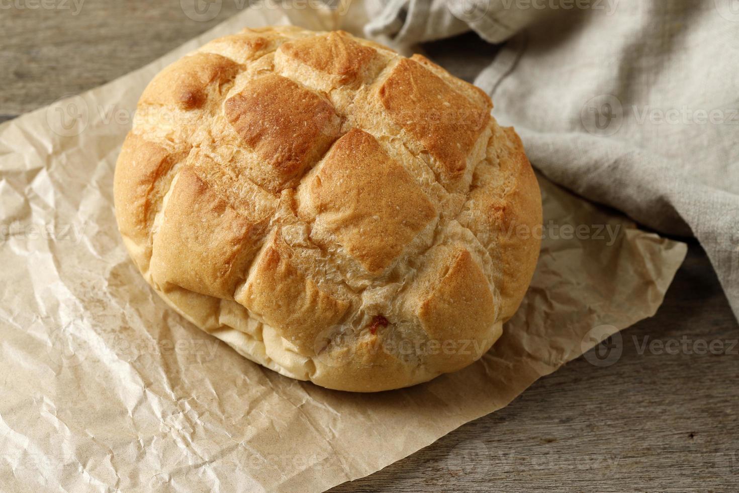 Homemade Boule Round Loaf Bread on Brown Paper, Rustic Wooden Table. photo