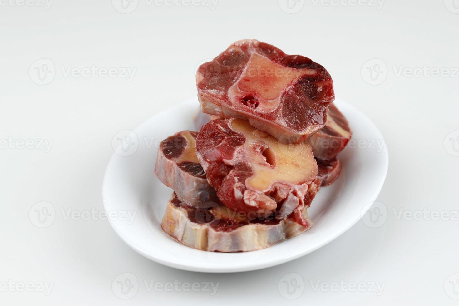 Raw Oxtail on WHite Plate, White Table, Copy Space for Text photo