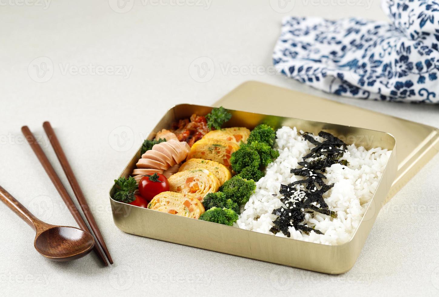 Korean Lunchbox Dosirak, Packed Meal Bento Lunchbox with various Banchan, Gyeran Mari, Tomato, Broccoli, Kimchi, and Sausage. photo