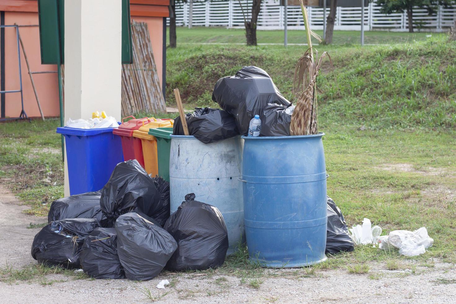The trash bin and a black bag to hold garbage that overflows out. photo