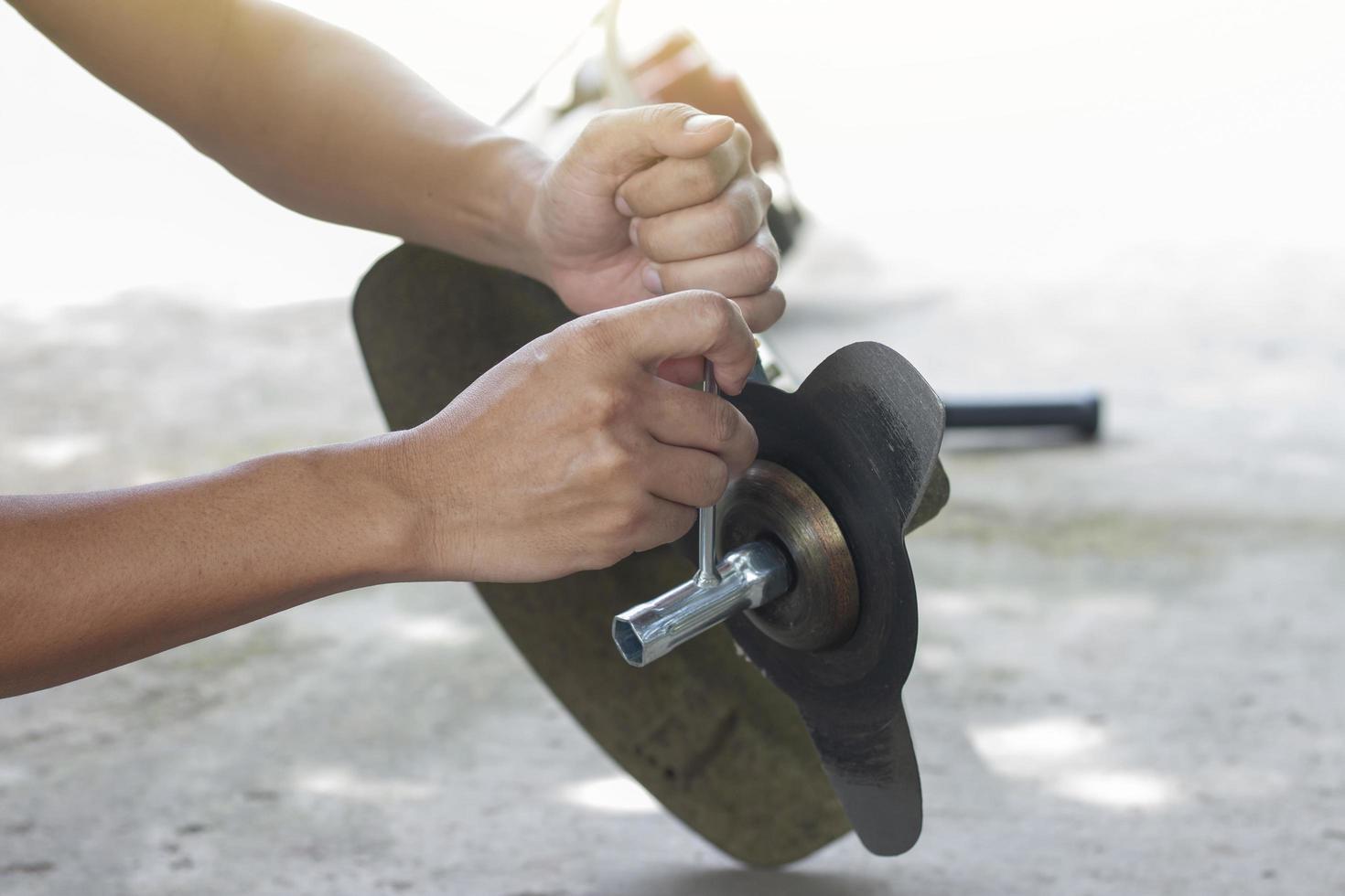 Hand of the mechanic holds the socket wrench to loosen the nut in the lawn mower. photo