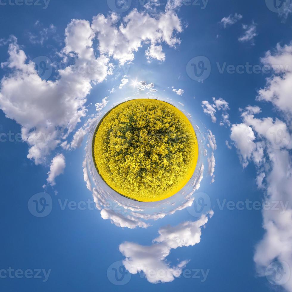 Little planet transformation of spherical panorama 360 degrees. Spherical abstract aerial view in rapeseed field with awesome beautiful clouds. Curvature of space. photo