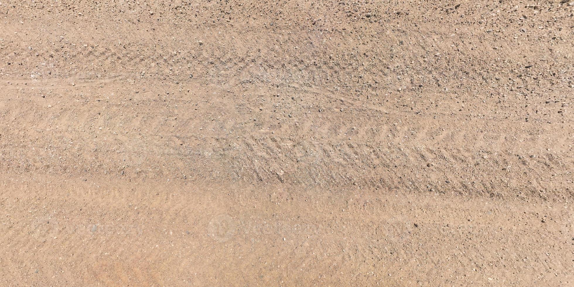 view from above on surface of gravel road with car tire tracks photo