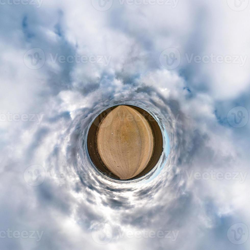 Little planet transformation of spherical panorama 360 degrees. Spherical abstract aerial view in field with awesome beautiful clouds. Curvature of space. photo