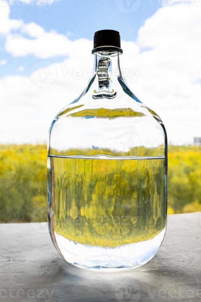 glass bottle with alcohol over colorful forest photo