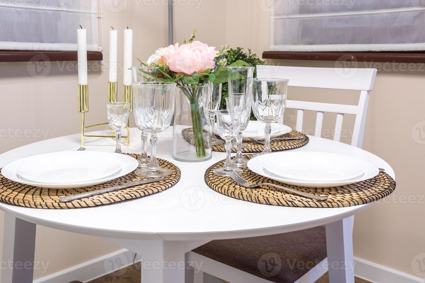 Closeup of empty wine glasses on banquet table with cutlery and Bouquet of yellow tulip flowers photo