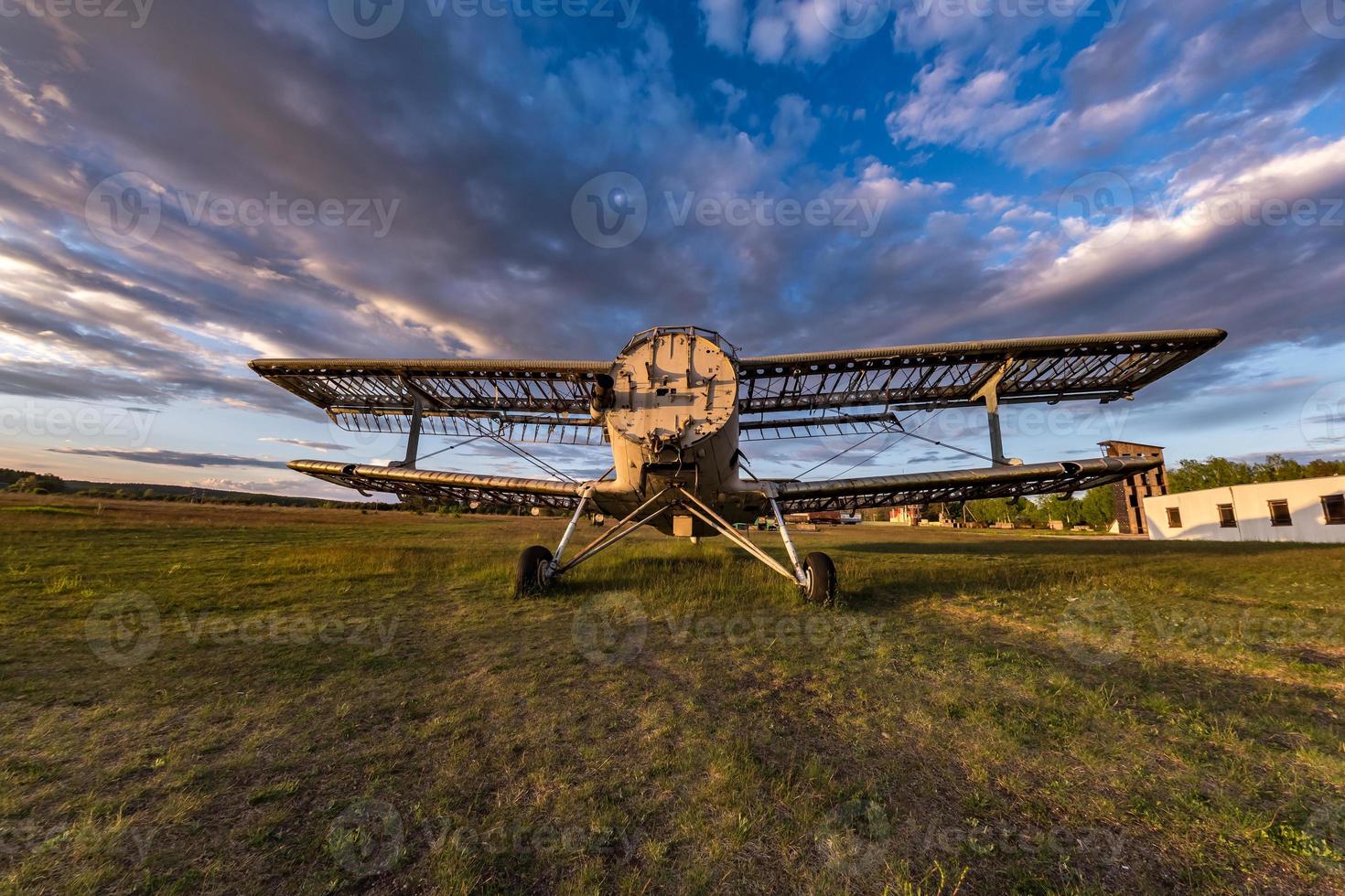 viejo avión destruido en el campo en los rayos del sol poniente con hermosas nubes foto