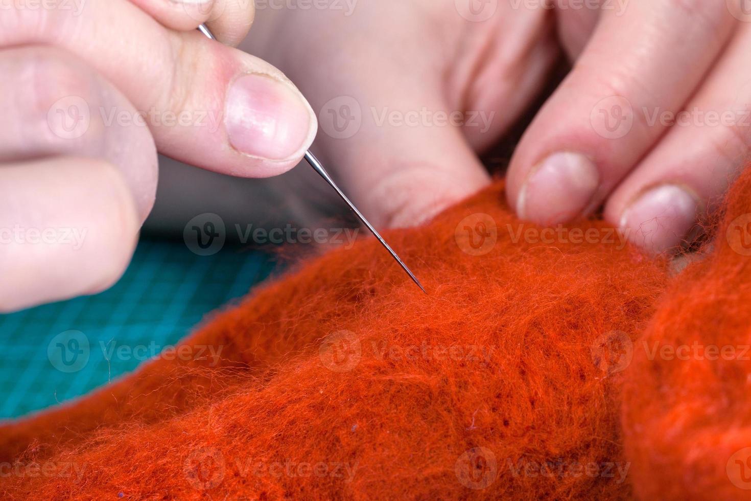 craftsman poking felted cloth with needle close up photo