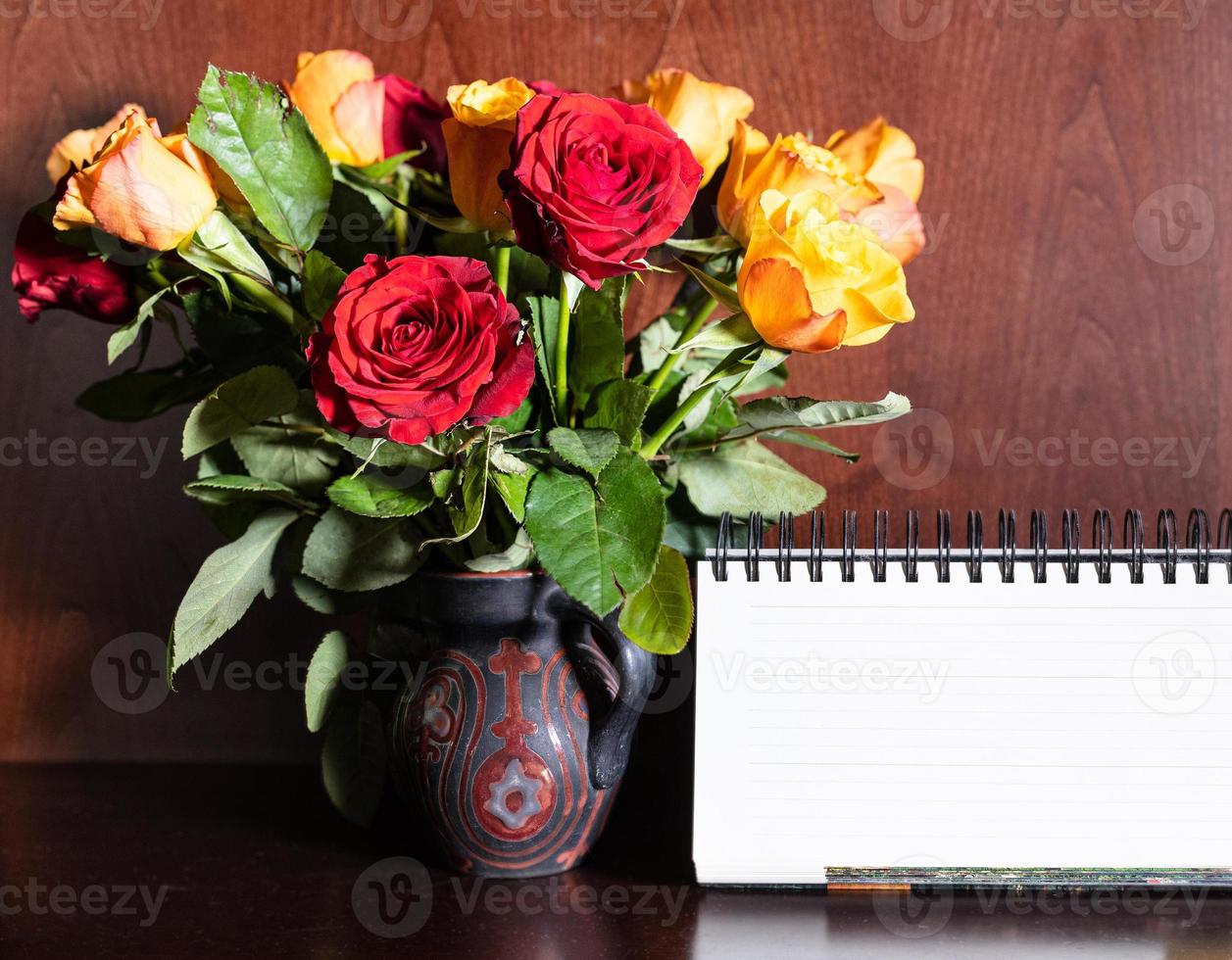 blank desk calendar and fresh red and yellow roses photo