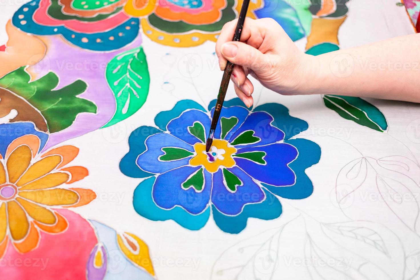 artist paints flower in batik on silk canvas photo