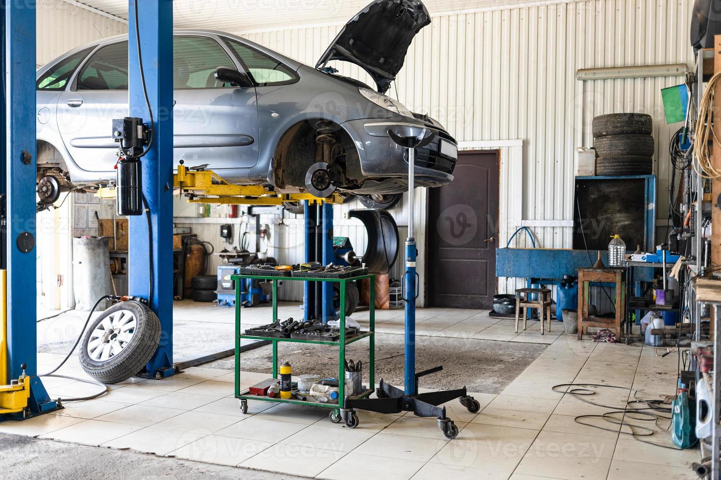 car is lifted on hydraulic lift in car workshop photo