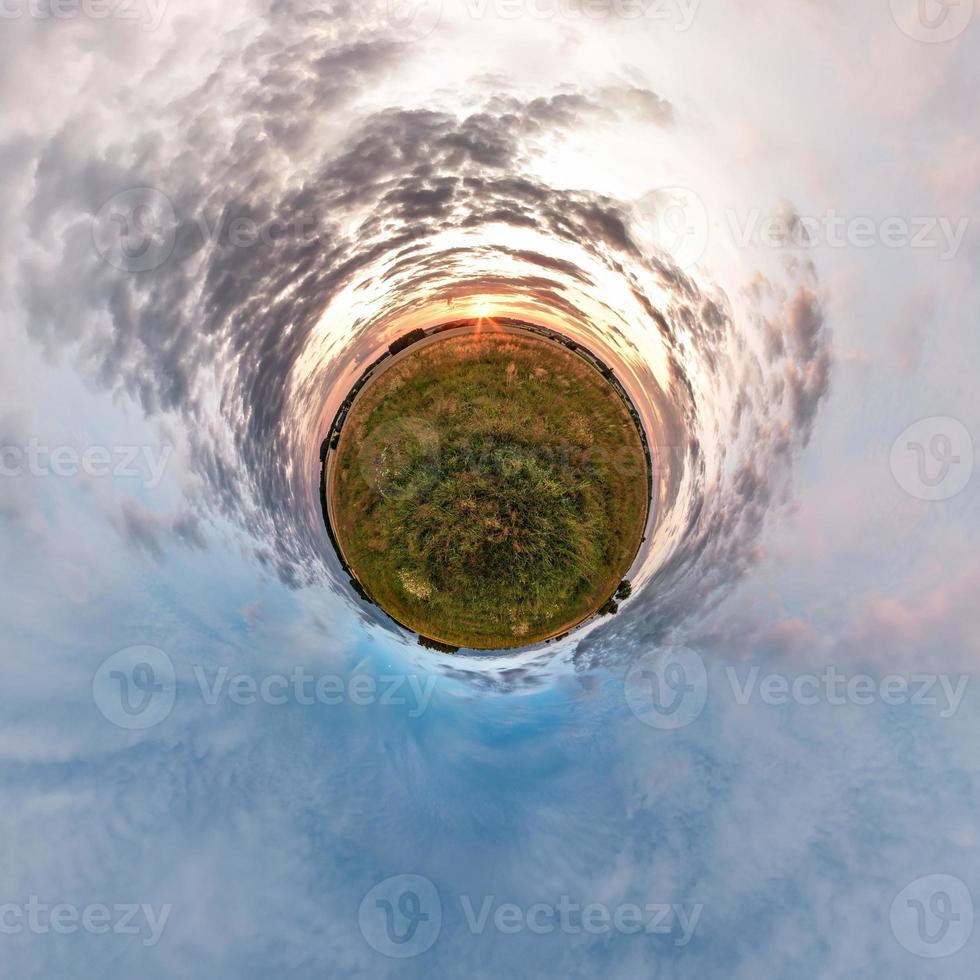 Little planet transformation of spherical panorama 360 degrees. Spherical abstract aerial view in field in nice evening with awesome beautiful clouds. Curvature of space. photo