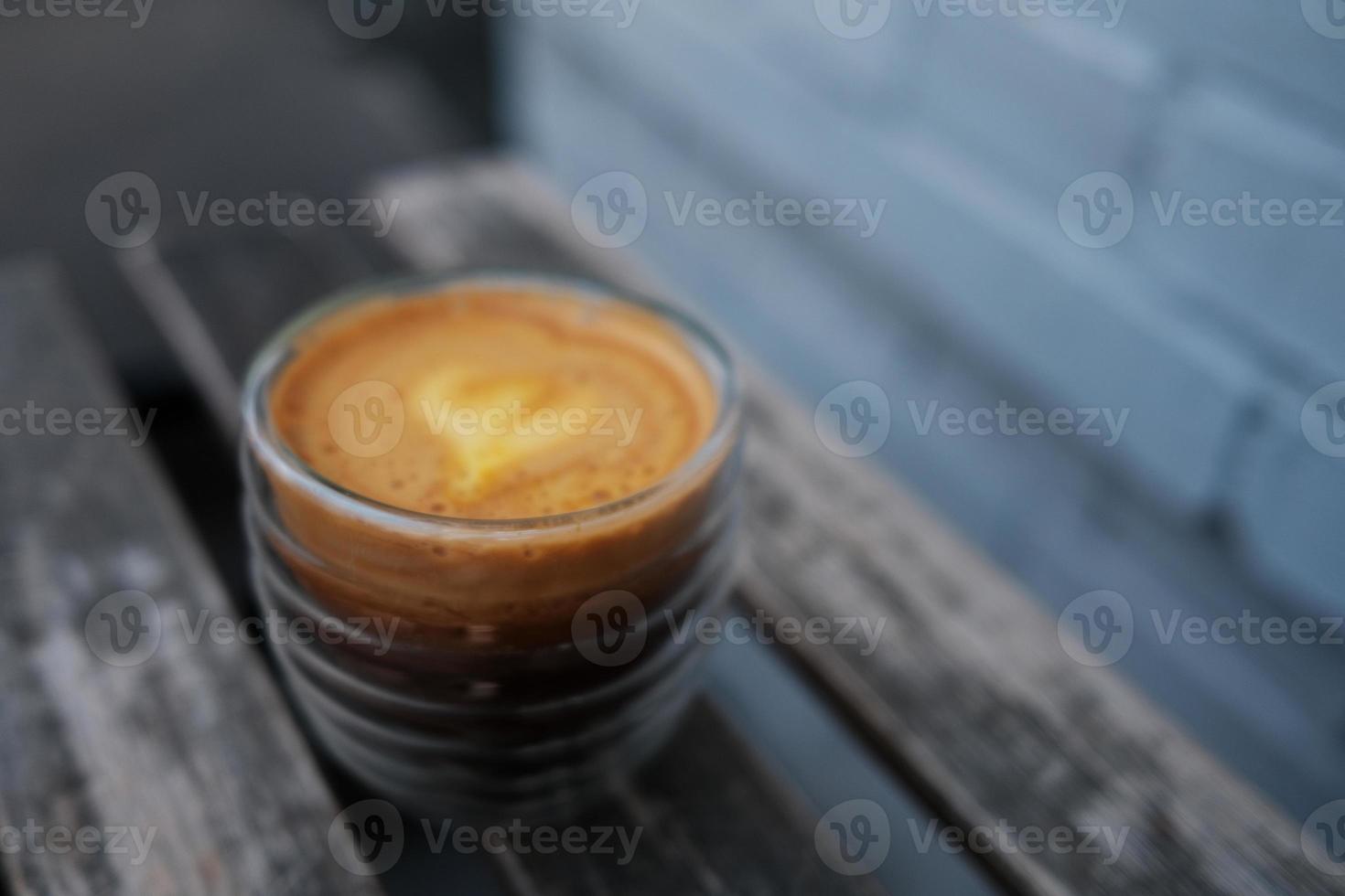 A cup of coffee stands on a wooden table against a brick wall. Focus on a drink, trendy capuorange mix of orange juice and an espresso. photo