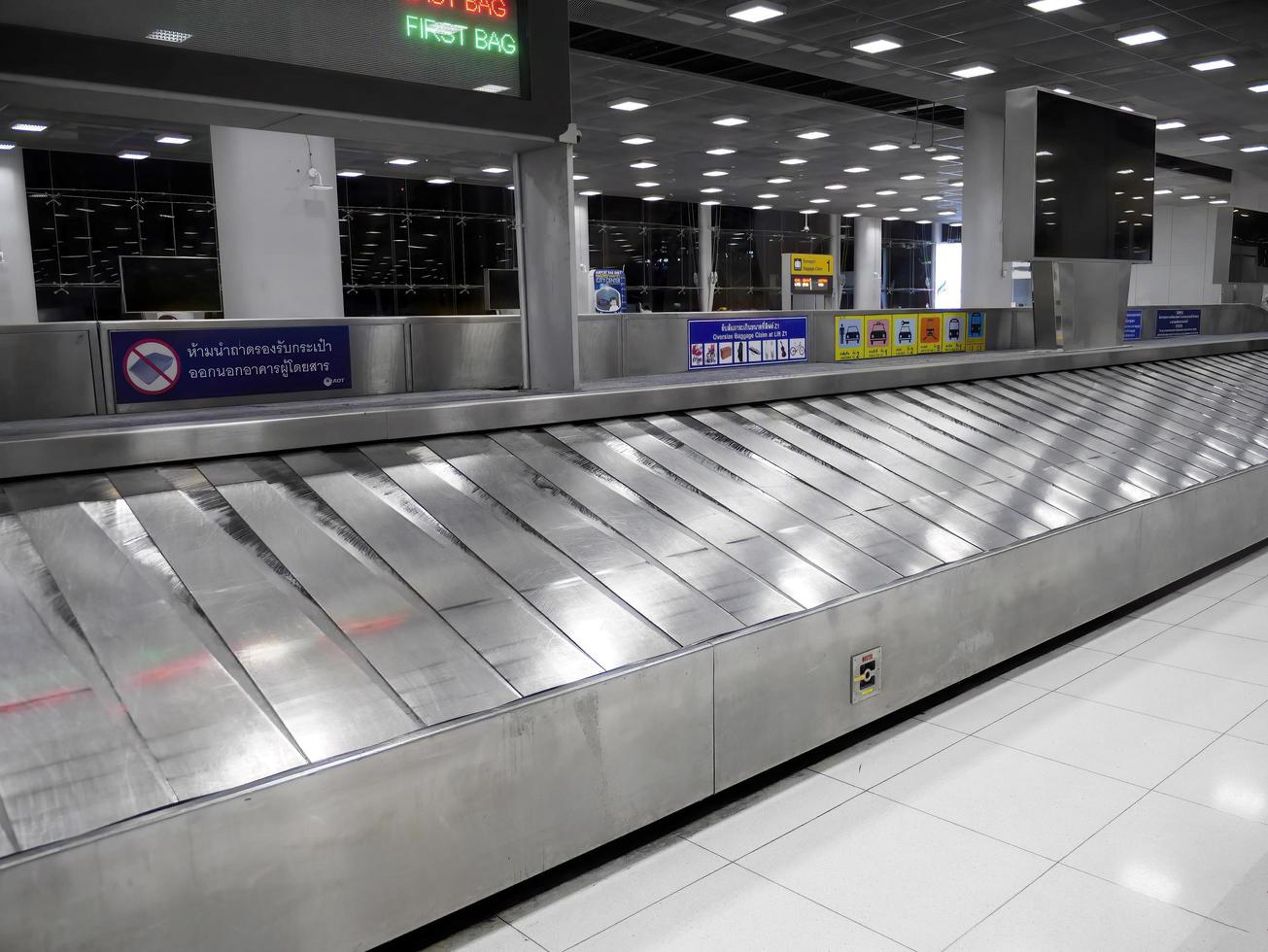 cinta transportadora en blanco en la terminal del aeropuerto internacional con señal de información gráfica del aeropuerto aeropuerto de bangkok tailandia foto