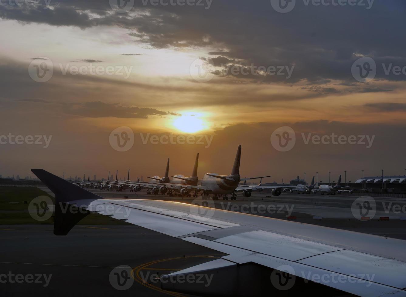 Airport with many airplanes at beautiful sunset, Aircraft fleet parked at taxiway of Bangkok International airport photo